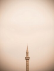 Minaret Reaching Skyward Amidst Hazy Light Urban Landscape