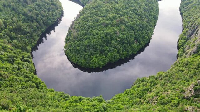 Winding river, tranquil bend, lush green hills, calm water reflections, idyllic