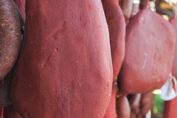 Traditional cured meats hanging in a rustic market stall