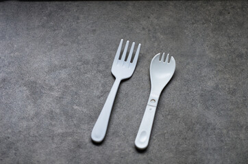 Two White Plastic Utensils on a Smooth Gray Surface