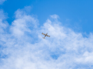 Small ultralight airplane with overhead wing and single propeller flying in sunset sky.