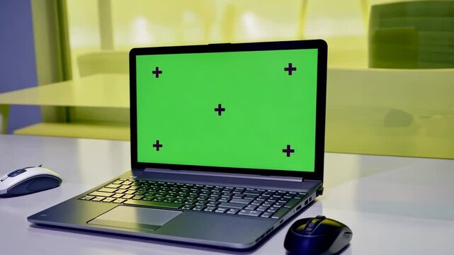 Laptop Computer Monitor Standing on a Desk with a Green Screen Chroma key. Green Screen Display with Isolated Placeholder.