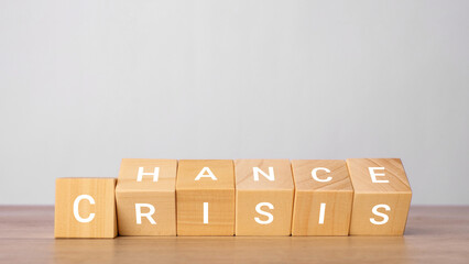 Wooden cubes crisis wording from change to chance on a wooden table with a light gray background....