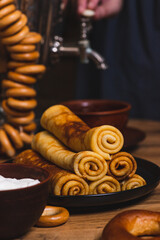 Rolled pancakes on a plate next to dryers and a samovar