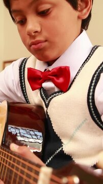 Cute pupil playing guitar in classroom
