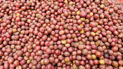 A pile of small, round, red-colored potatoes is displayed for sale in the market.
