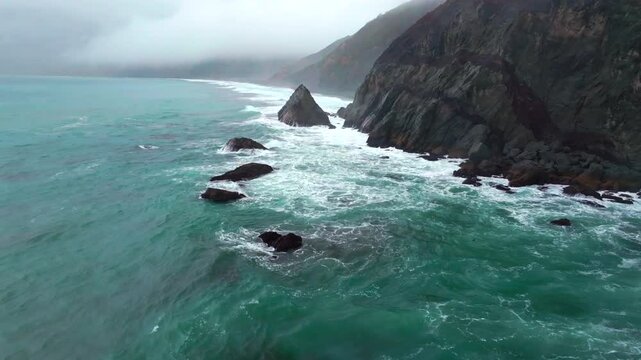 Rugged dramatic untouched coastline aerial drone California surf waves crashing boulder rocks USAL Beach campground cloud layer mist rain fog PNW Lost Coast Trail morning nature landscape forwards