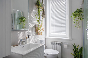 Stylish clean white bathroom with light gray tiles on the walls and lots of indoor plants.