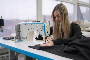 A skilled seamstress carefully stitches fabric on a sewing machine, surrounded by sunlight in a vibrant workshop