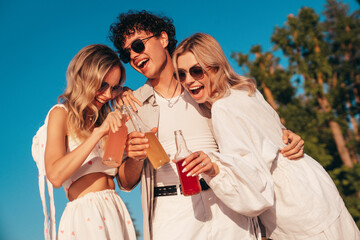 Young stylish friends posing at the seaside. Fashion man and two cute female dressed in casual...