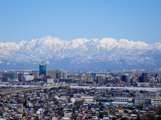冠雪の北アルプス剱立山連峰と雪化粧の富山市街地
