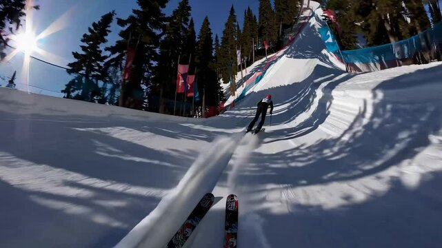 POV video of a skier racing downhill on a snowy slope, surrounded by flags and trees, capturing the thrill and speed of the descent.
