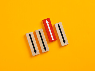 Red wooden block standing out from the crowd with up arrow on yellow background