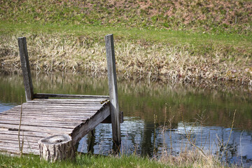 
a small wooden bridge that spans a small pond or ditch.