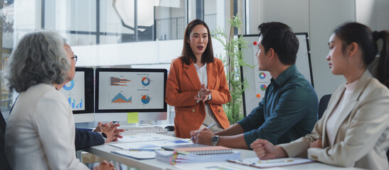 Asian businesswoman leading a meeting, presenting marketing data analysis displayed on computer...