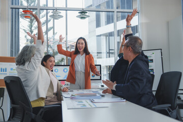 Euphoric businesspeople are raising their hands and cheering, celebrating a successful project or...