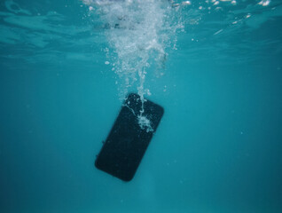 Smartphone sinking underwater with bubbles and splash