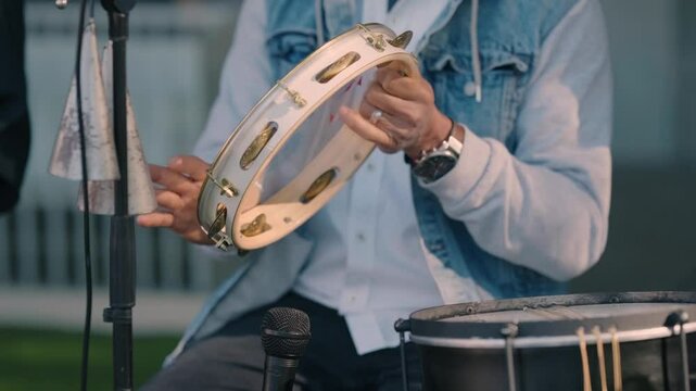 Close up of a musician playing a tambourine during an outdoor live performance