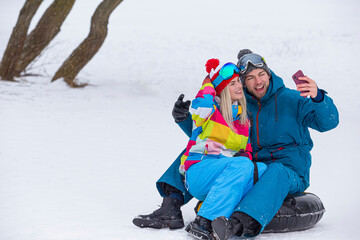 Portrait of One Happy Laughing Caucasian Couple Having Tube Activities In Winter Time And Posing Together For Taking Selfie.