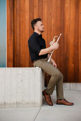 Confident trumpet player and teacher poses outdoors in natural light