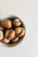 Overhead view of brown mushrooms in bowl white background