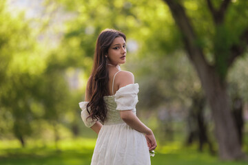 Beautiful Girl with long hair poses near white blossoming apple trees