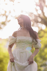 Beautiful Girl with long hair poses near white blossoming apple trees