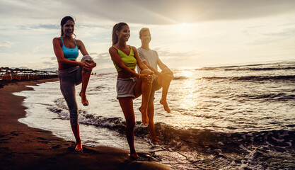 Group of people practicing healthy lifestyle, yoga on beach. Balance in yoga position together.