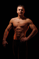 Fototapeta premium Adult male athlete bodybuilder posing on a orange light