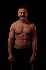 Fototapeta premium Adult male athlete bodybuilder posing on a orange light