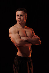 Adult male athlete bodybuilder posing on a orange light