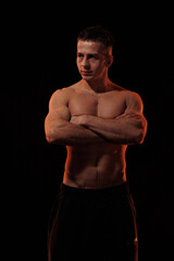 Fototapeta premium Adult male athlete bodybuilder posing on a orange light