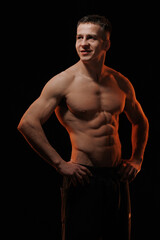 Fototapeta premium Adult male athlete bodybuilder posing on a orange light