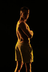 Naklejka premium Adult male athlete bodybuilder posing on a orange light 