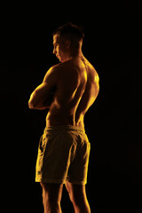 Fototapeta premium Adult male athlete bodybuilder posing on a orange light 