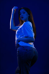 Young girl posing and moving in a black studio with colored light