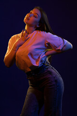 Young girl posing and moving in a black studio with colored light