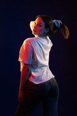 Young girl posing and moving in a black studio with colored light