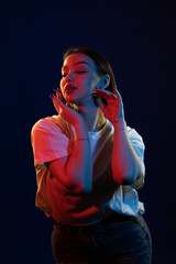 Young girl posing and moving in a black studio with colored light	