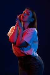 Young girl posing and moving in a black studio with colored light	