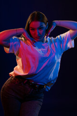 Young girl posing and moving in a black studio with colored light	