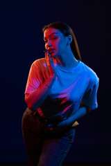 Young girl posing and moving in a black studio with colored light	