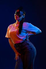 Young girl posing and moving in a black studio with colored light	
