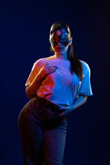 Young girl posing and moving in a black studio with colored light	