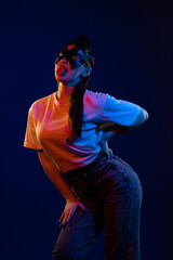 Young girl posing and moving in a black studio with colored light	