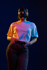 Young girl posing and moving in a black studio with colored light	
