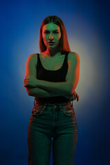 Young girl posing and moving in a black studio with colored light	