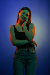 Young girl posing and moving in a black studio with colored light	