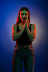 Young girl posing and moving in a black studio with colored light	