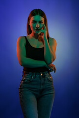 Young girl posing and moving in a black studio with colored light	